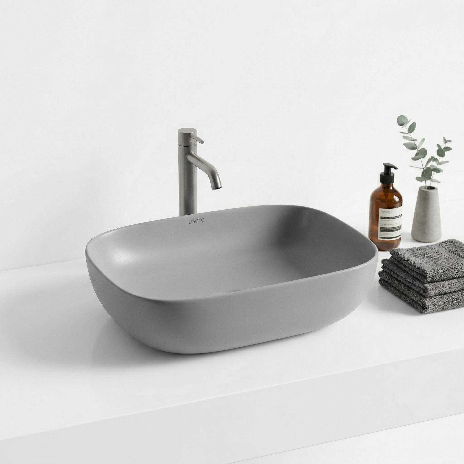 Gray table top sink with faucet on a white countertop with cleaning supplies.