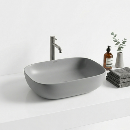Gray table top sink with faucet on a white countertop with cleaning supplies.
